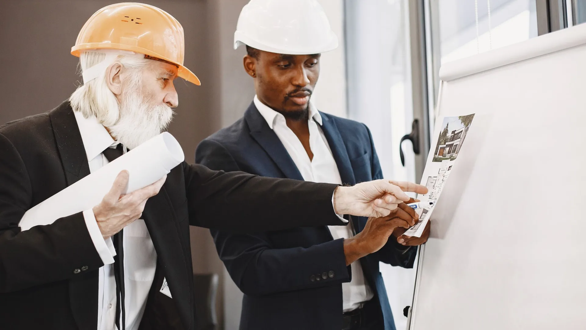 Experienced professional mentoring a colleague while reviewing project plans